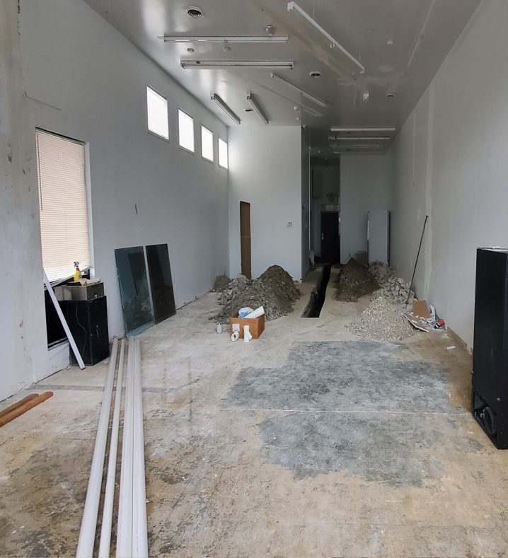 Coffee shop before: bare concrete floor trenched for plumbing, unfinished walls